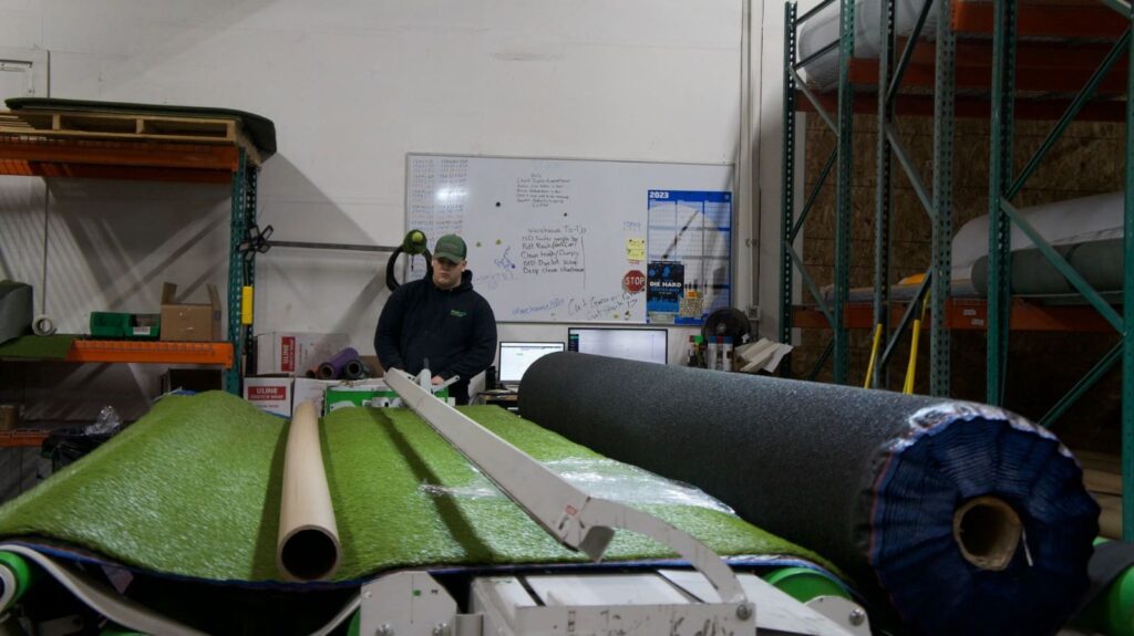 Synthetic Turf Northwest - Turf Cutting Machine. A man cutting turf at a large machine
